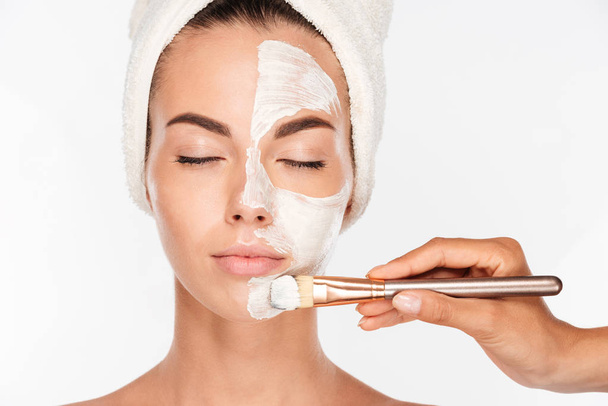 Woman getting beauty skin mask treatment on face with brush - Foto, Imagen