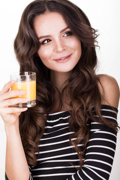 Beautiful woman with healthy skin, hair curls and orange juice, posing in studio. Beauty face. - Photo, Image