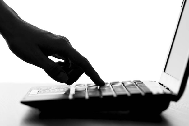 silueta del dedo de una mano femenina pulse una tecla en el teclado del netbook
 - Foto, Imagen