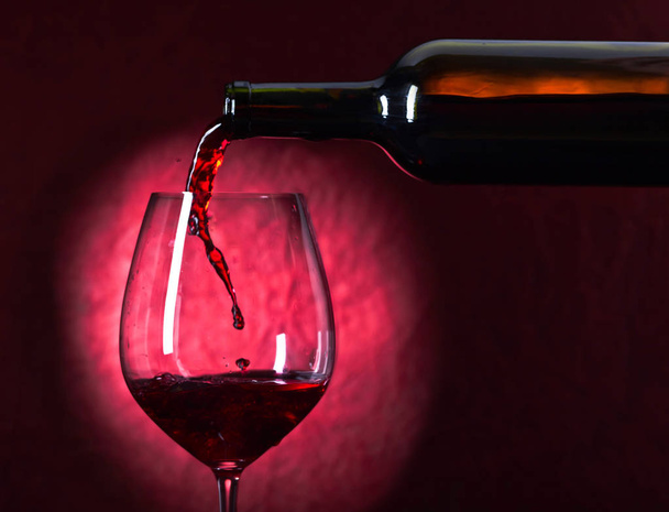 Fles en glas rode wijn op een donkere achtergrond - Foto, afbeelding