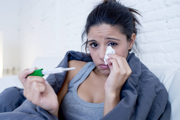 joven mujer hispana atractiva acostada enferma en el sofá de casa en el resfriado y la gripe en la enfermedad de gripe síntoma
 - Foto, imagen