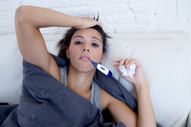young attractive hispanic woman lying sick at home couch in cold and flu  in gripe disease symptom - Fotografie, Obrázek