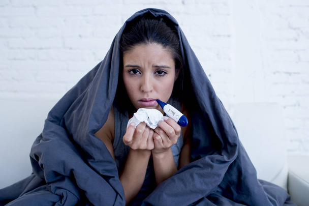 joven mujer hispana atractiva acostada enferma en el sofá de casa en el resfriado y la gripe en la enfermedad de gripe síntoma
 - Foto, Imagen