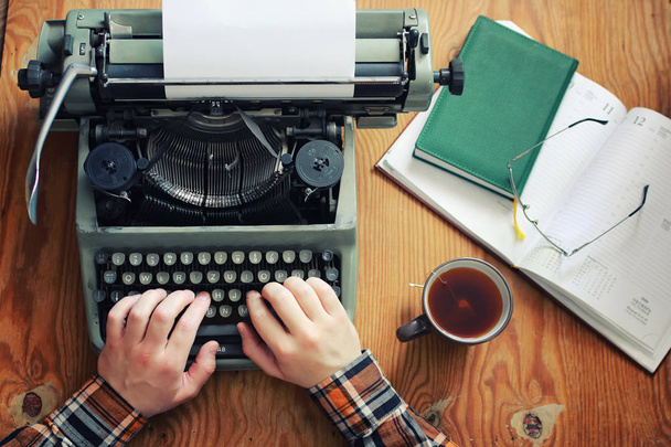 Ретро-рука пишущей машинки на деревянном столе
 - Фото, изображение
