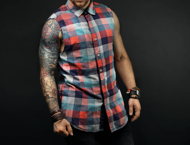 Young tattooed man posing on dark background - Фото, зображення