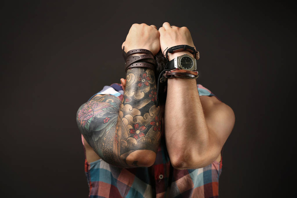 Young tattooed man posing on dark background - Valokuva, kuva