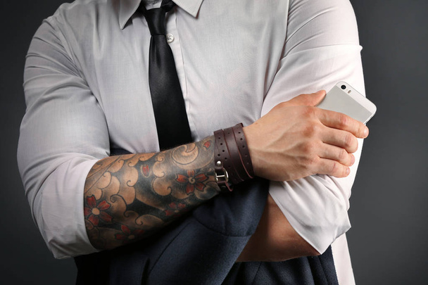 Young tattooed man posing on dark background - Foto, Imagem