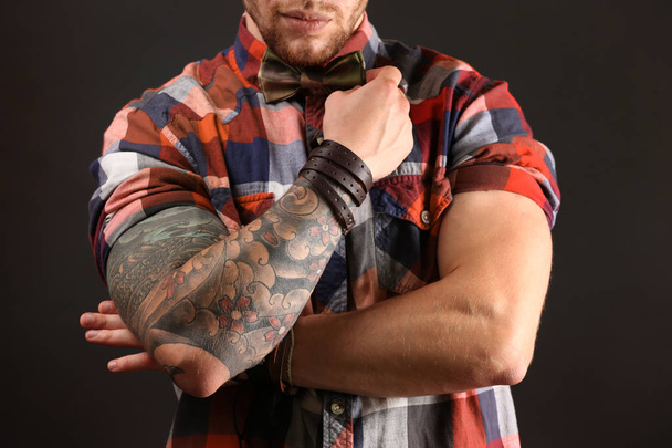 Young tattooed man posing on dark background - Fotó, kép