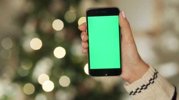 Primer plano de las manos femeninas tocando el teléfono inteligente. Llave de croma de pantalla verde. De cerca. Movimiento de rastreo. con fondo borroso decoración de Navidad
 - Imágenes, Vídeo