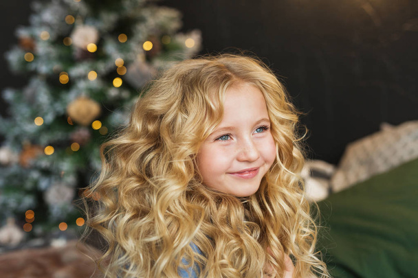 Portrait of pretty blonde little girl smiles and looks side in Christmas time - Foto, Imagen