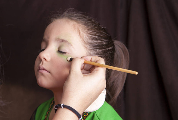 Little cute girl making facepaint before halloween party - Photo, image