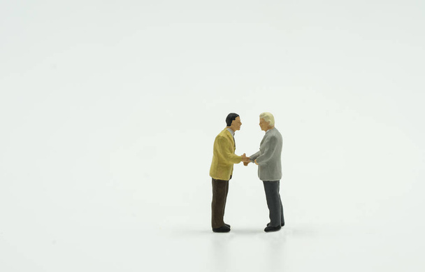 twee mini zakenman shake hand op isoleren achtergrond - Foto, afbeelding