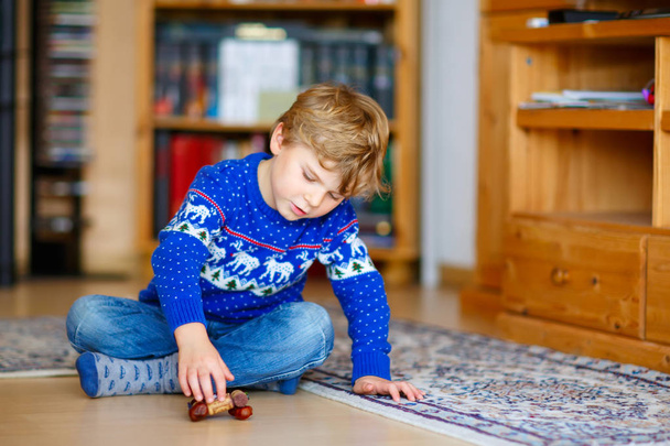 Niño pequeño jugando con juguete de castaño hecho a mano en el interior
 - Foto, imagen