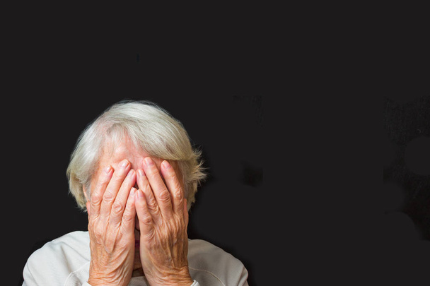 Portrait d'une femme âgée avec le visage fermé par les mains sur le noir
 - Photo, image