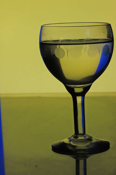 glass of water on blue yellow background - Foto, Imagem