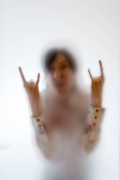 Женщина делает жест камня за матовым стеклом
 - Фото, изображение