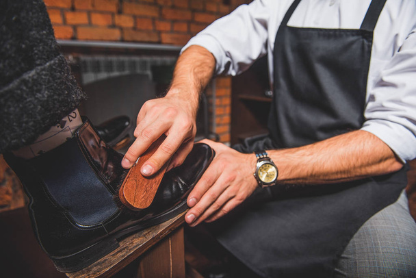 craftsman shoe shining footwear in front of him - Fotoğraf, Görsel