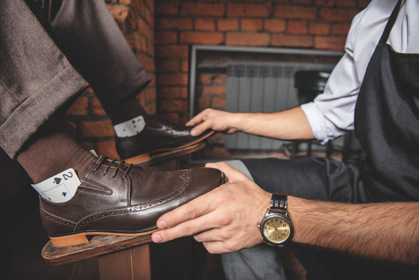 artisan touching footwear of his client - 写真・画像