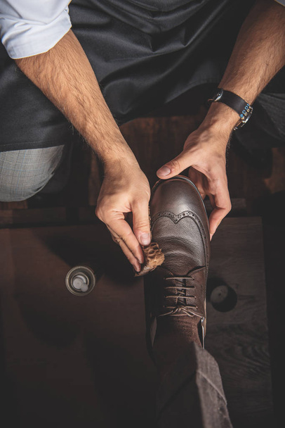 man washing leather brogues with a sponge - 写真・画像
