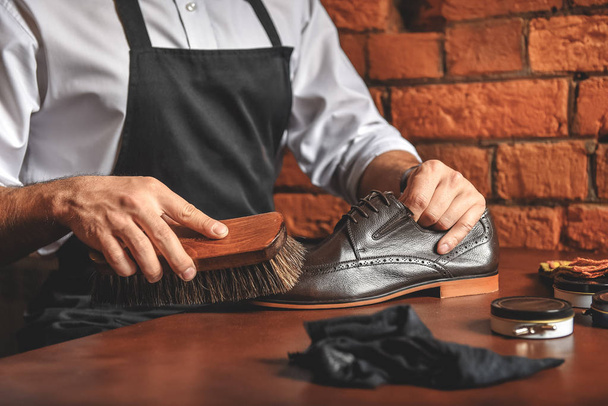 artisan in apron taking care of elegant boots - Fotografie, Obrázek