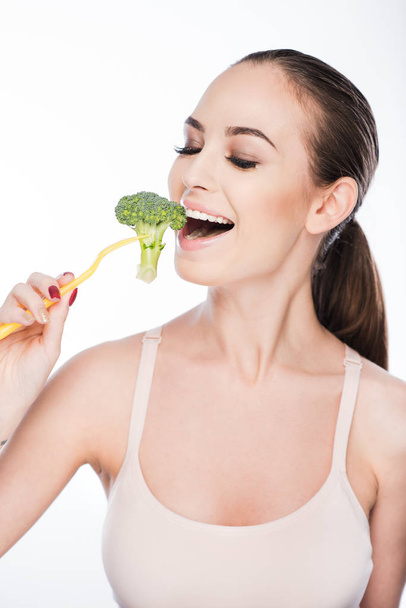 Thin young woman eating green vegetable - Fotó, kép