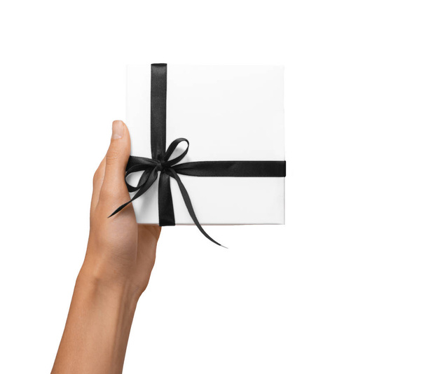 İzole kadın tatil hediyesi beyaz kutu beyaz arka plan üzerinde koyu siyah kurdele ile holding eller - Fotoğraf, Görsel