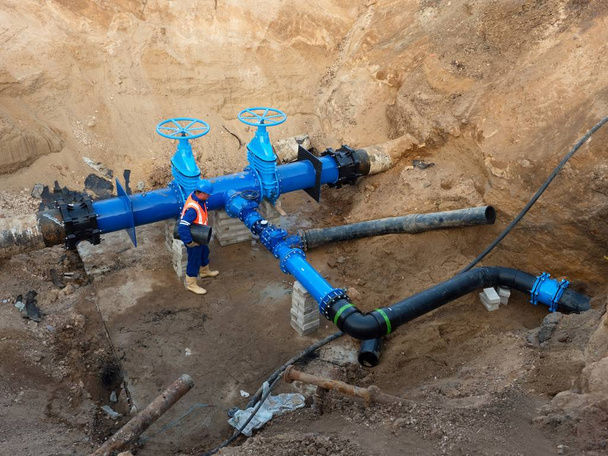 Expert technique souterrain à vanne sur conduites d'eau potable 500mm. Vérifier la tuyauterie réparée avant de la recouvrir d'argile. Isolement asphalte
 - Photo, image