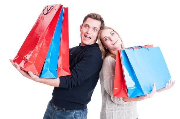 feliz casal segurando pesados sacos de compras e agindo espantado
 - Foto, Imagem