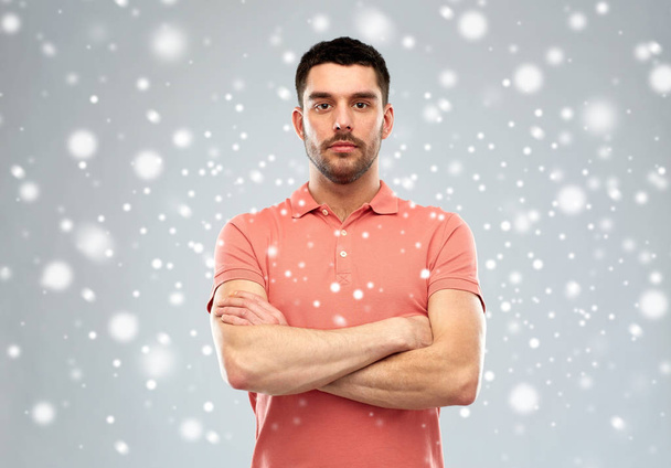 young man with crossed arms over snow background - Foto, imagen