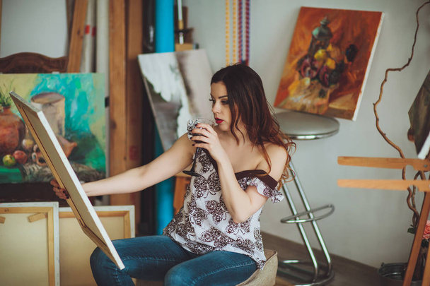 Woman artist painting a picture in a studio - Valokuva, kuva