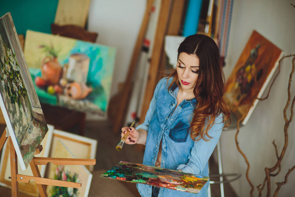 Nainen taiteilija maalaamassa kuvaa studiossa
 - Valokuva, kuva