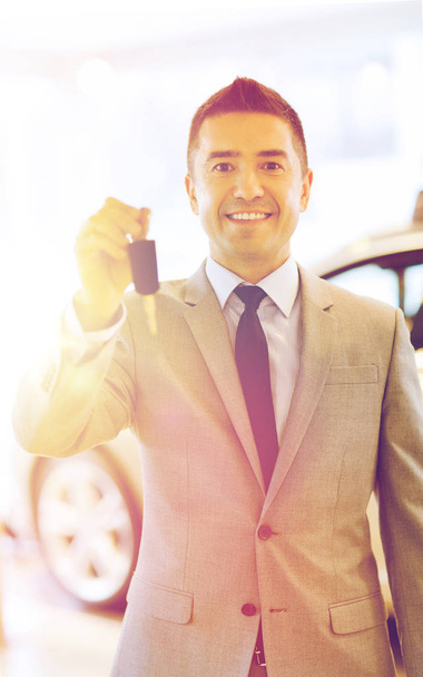 happy man showing key at auto show or car salon - Fotó, kép