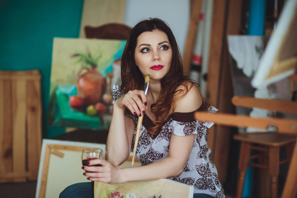 Γυναίκα καλλιτέχνης να ζωγραφίζουν μια εικόνα σε ένα στούντιο. Δημιουργική συλλογισμένος ζωγράφος κοπέλα ζωγραφίζει μια πολύχρωμη εικόνα σε καμβά με λάδι χρώματα στο εργαστήριο. - Φωτογραφία, εικόνα