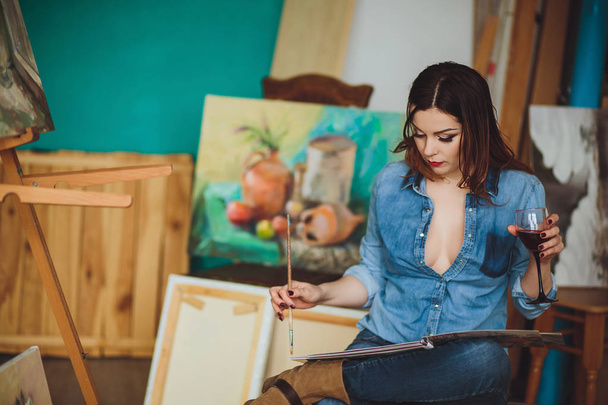 Artista mujer pintando un cuadro en un estudio. Creativo pensativo pintor niña pinta un cuadro colorido sobre lienzo con colores al óleo en el taller
. - Foto, imagen