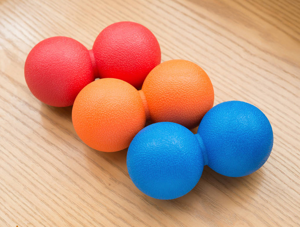petites boules de massage rouges et orange et bleues sur une table en bois
 - Photo, image