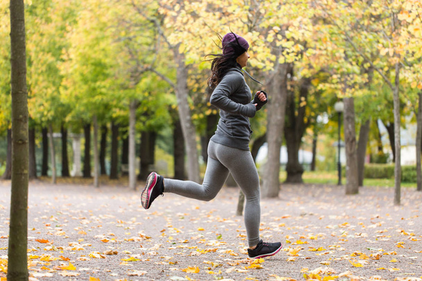 close up of young woman running in autumn park - 写真・画像
