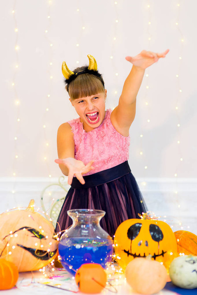 Teenager girl in demon costume posing with pumpkins - Foto, afbeelding