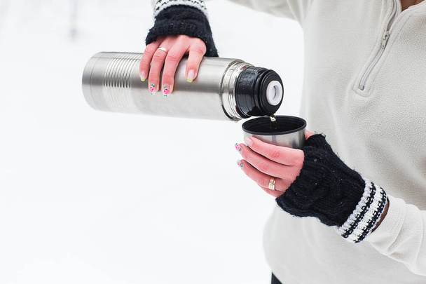 Woman pours and drinks tea from a thermos after jogging - Foto, Bild