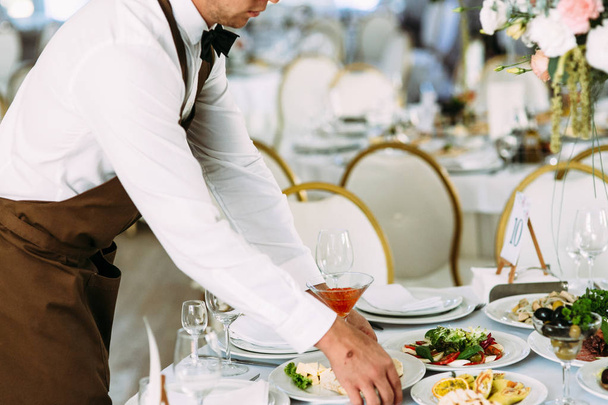 Waiter puts a plate with food on the table - Photo, image