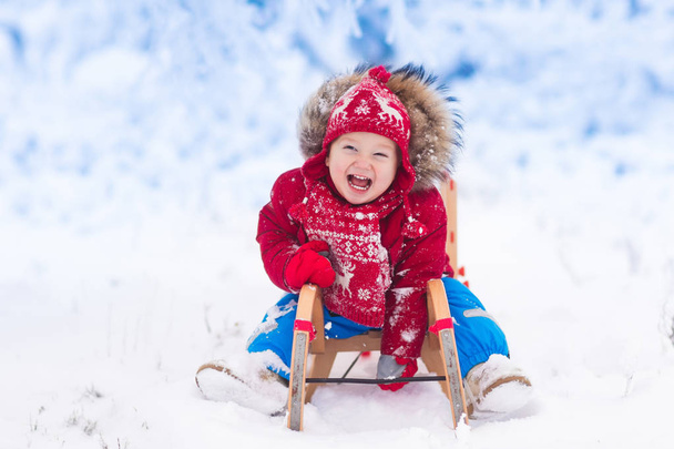 Kinderen spelen in de sneeuw. Winter sleigh ride voor kinderen - Foto, afbeelding