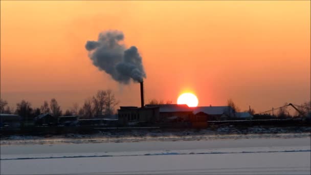 environmental pollution with harmful gases. smoke from the chimney is released into the air against the backdrop of the setting sun next to the river. an environmental problem. winter. - Footage, Video