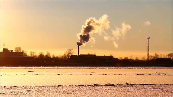 Umweltverschmutzung durch schädliche Gase. Vor dem Hintergrund der untergehenden Sonne am Fluss wird Rauch aus dem Schornstein in die Luft freigesetzt. ein Umweltproblem. Winter. - Filmmaterial, Video