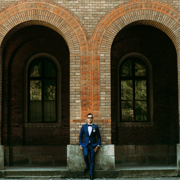 Handsome groom stands next to the arch - Fotó, kép