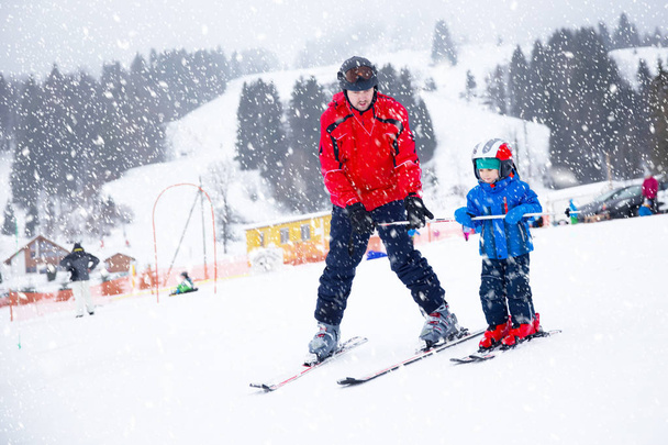 Happy little boy learning skiing with his father in Swiss Alps - Photo, Image