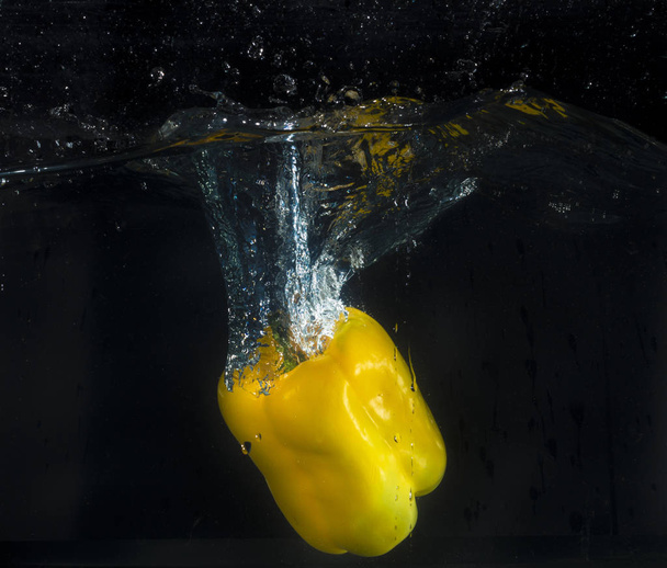 Pimenta amarela salpicando na água com bolhas
 - Foto, Imagem