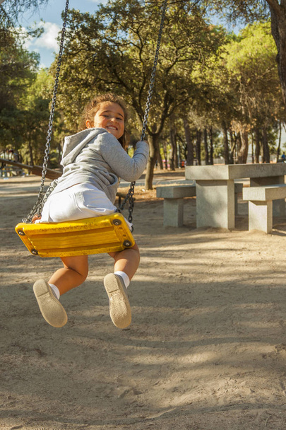 Rear view girl having fun on swing at the playground - 写真・画像