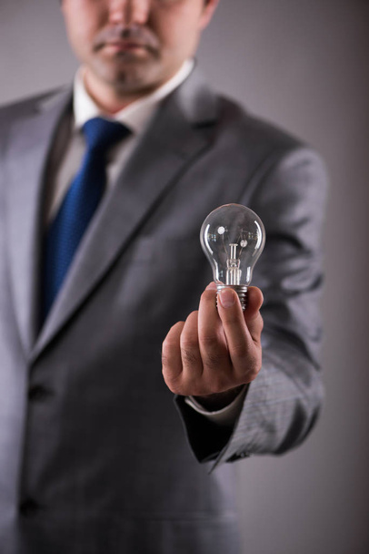 Businessman holding light bulb in creativity concept - Valokuva, kuva