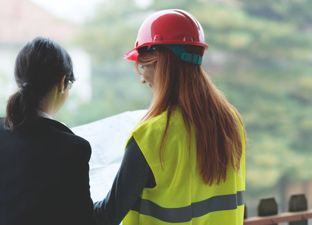 Smiling young female investor and smiling young redhead female architect working.  - Photo, Image