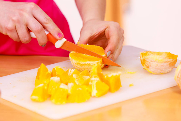 Woman housewife in kitchen cutting orange fruits - Foto, Imagen