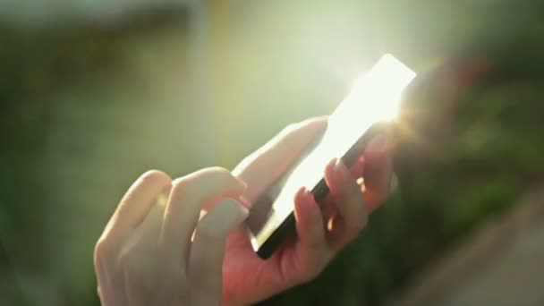 Kadın sms manifatura app günbatımında güneş objektif parlama ile akıllı telefon kullanarak - Video, Çekim